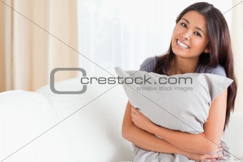 charming woman with pillow in her arms looking into camera