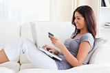 smiling woman sitting on sofa holding creditcard