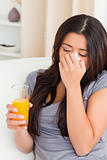 sad woman with orange juice on sofa