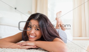 close up of a cute woman lying on a carpet smiling into camera