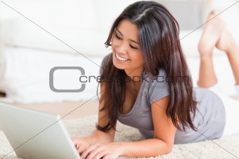 close up of a smiling woman lying on a carpet with notebook 