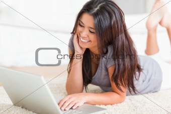 close up of a charming woman lying on a carpet with notebook 