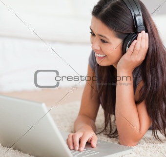 close up of a charming woman lying on a carpet with laptop and e