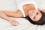 close up of a brunette smiling woman lying on bed