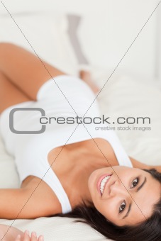 close up of a brunette charming woman lying on bed