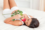 cute woman with rose lying on bed