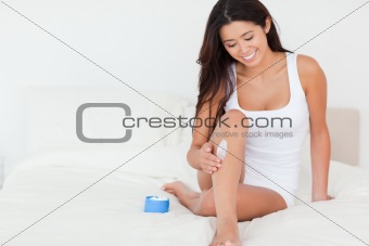 cute woman putting cream on her legs 