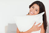 close up of a charming woman with pillow sitting on her bed look