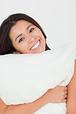 close up of a cute woman with pillow sitting on her bed looking 