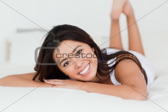 close up of a brunette woman lying on bed with crossed legs
