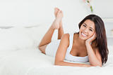 happy woman lying on bed with crossed legs looking into camera