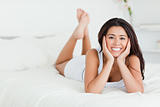 goodlooking woman lying on bed with crossed legs looking into ca