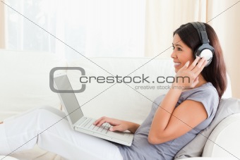 smiling woman sitting on sofa wearing earphones