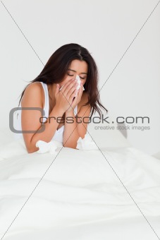 brunette woman having a cold sitting in bed
