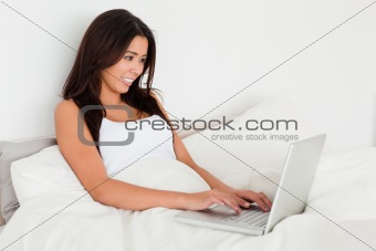 dark-haired woman with notebook lying in bed