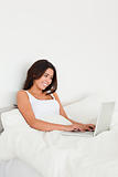 smiling woman with notebook lying in bed 