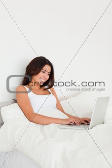 smiling woman with notebook lying in bed 