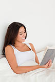cute woman reading book lying in bed 