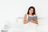 dark-haired woman reading book lyling in bed