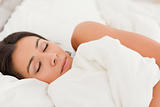 sleeping brunette woman lying under sheet