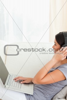 brunette woman sitting on sofa working with notebook 