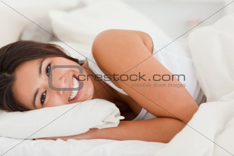 close up of a smiling cute woman lying under sheet