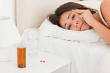 close up of a  cute woman lying under sheet having headache look