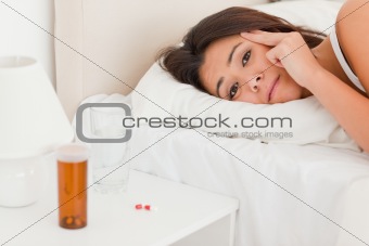 close up of a  cute woman lying under sheet having headache look