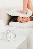 woman waking under sheet not wanting to hear alarm clock
