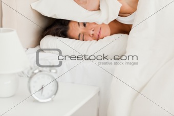 close up of a woman waking under sheet not wanting to hear alarm