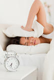 cute woman waking under sheet not wanting to hear alarm clock