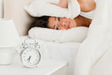goodlooking woman waking under sheet not wanting to hear alarm c