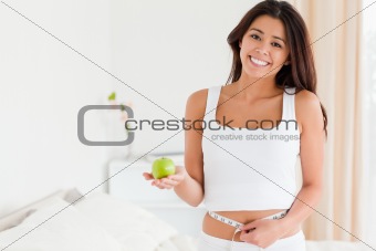 gorgeous woman measuring her waist while holding an apple