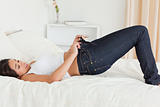 pretty woman lying on bed trying to close her jeans