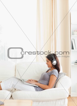 smiling woman with earphones sitting on sofa