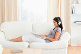 charming woman with earphones sitting on sofa