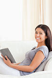 charming woman reading a book sitting on sofa smiles into camera