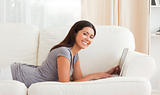 cute woman lying on sofa with notebook