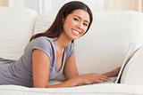 close up of a charming woman lying on sofa with notebook smiling