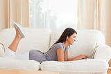 smiling woman lying on sofa with notebook in front