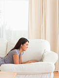 smiling woman lying on sofa with notebook in front of her