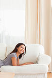 woman lying on sofa with notebook in front of her smiling into c