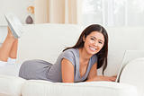 cute woman lying on sofa with notebook in front of her smiling i