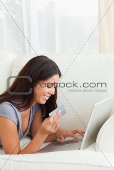 charming woman with card in hand lying on sofa