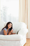 happy woman with card in hand lying on sofa looking into camera