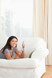 woman with thumb up and card in hand lying on sofa looking into 
