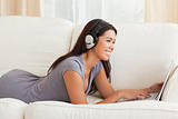 smiling woman with earphones lying on sofa