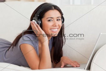 close up of a charming woman with earphones lying on sofa lookin