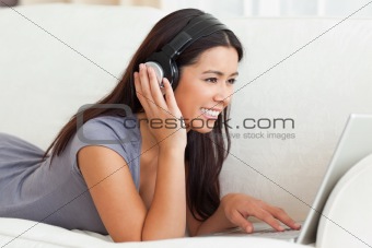 close up of a charming woman with earphones lying on sofa