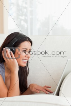 charming woman with earphones lying on sofa